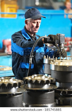 adult industrial worker during heavy industry machinery assembling on production line manufacturing workshop at factory