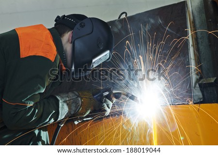 welder working with electrode at semi-automatic arc welding in manufacture production plant