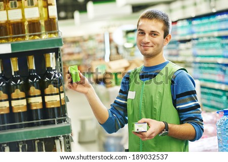 Merchandising. Sales assistant in supermarket lay out goods on supermarket shelves at store