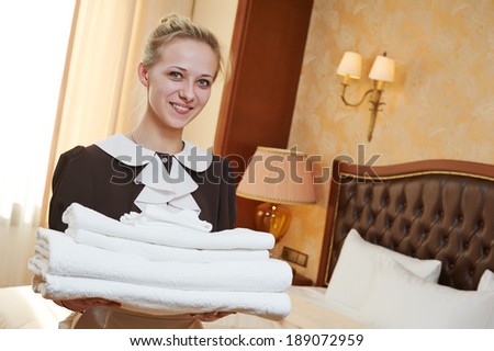Hotel service. female chambermaid or housekeeping worker with towels and bedclothes at inn room
