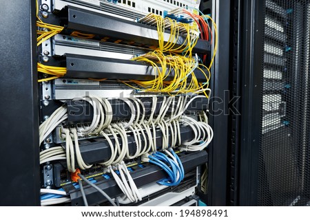 technology equipment with optical fibre cables connected to rack servers in room