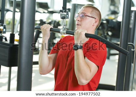 fitness man doing muscles exercises with training weight machine station in gym