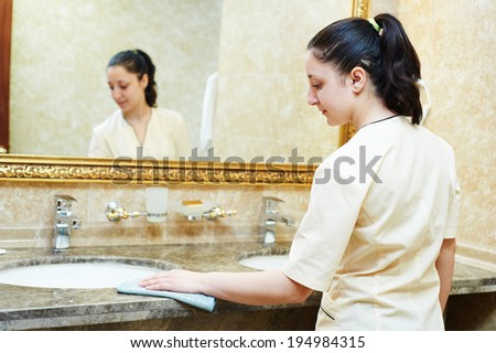 Hotel service. female housekeeping worker cleaning table from dust in bathroom