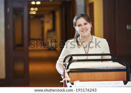 Hotel room service. female housekeeping worker with bedclothes linen in cart