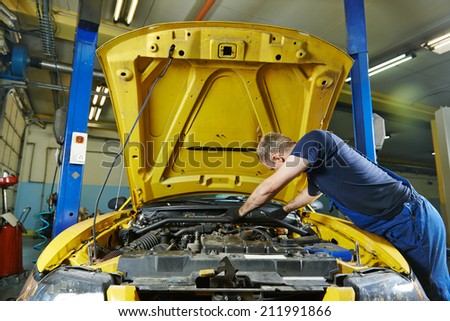 auto mechanic repairman tighten screw with spanner during automobile car maintenance at engine repair service station garage
