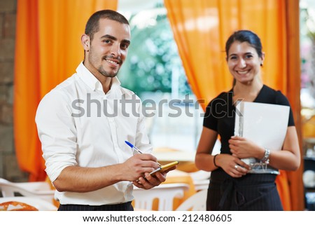 Waitress girl and waiter man of commercial restaurant in uniform waiting an order with menu