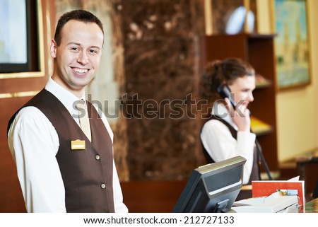 Happy receptionist worker standing at hotel counter