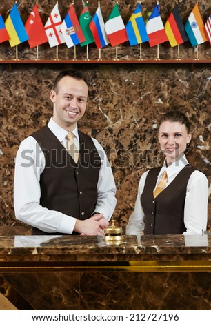 Happy receptionist workers standing at hotel counter