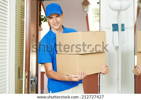 Smiling male postal delivery courier man indoors delivering parcel package boxes