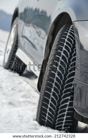 Car with winter tyres installed on light alloy wheels in snowy outdoors road