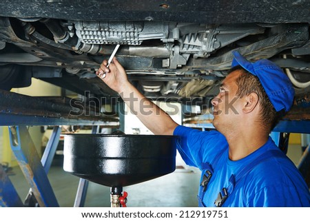 auto mechanic technician replacing and changing motor oil in automobile engine at maintenance repair service station