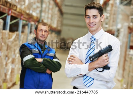 smiling manager and worker in warehouse with bar code scanner