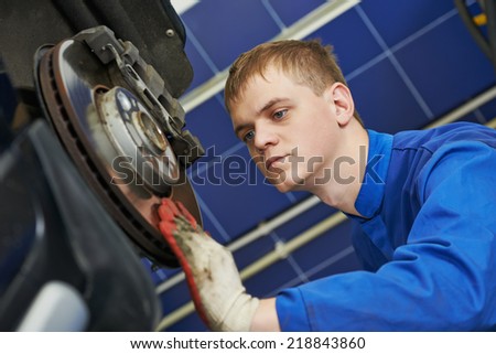car mechanic examining car wheel brake disc and shoes of lifted automobile at repair service station