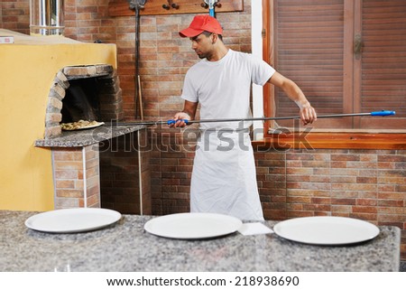 chef baker man in uniform making pizza at restaurant kitchen stove