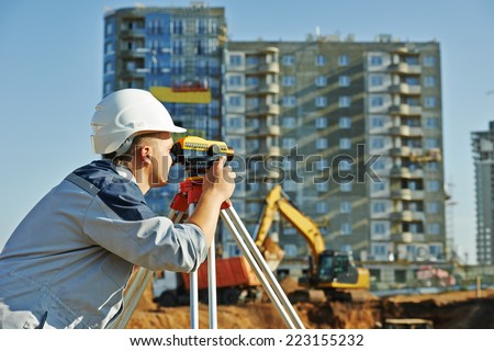 Surveyor builder worker with theodolite transit equipment at construction site outdoors during surveying work