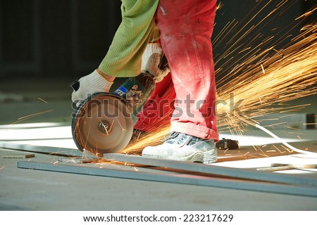 Construction builder worker with grinder machine cutting metal bar at building site