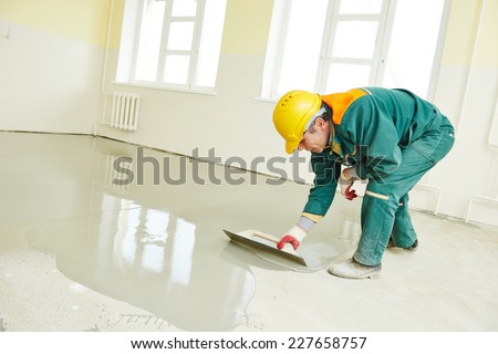 plasterer during floor covering works with self-levelling cement mortar