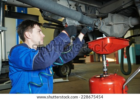 auto repairman mechanic disassembling axle reduction gear with wrench in car auto repair or maintenance shop service station