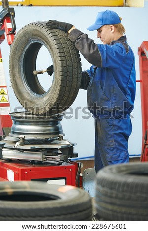 Auto repairman lubricating automobile car wheel during tyre fitting or tire replacing