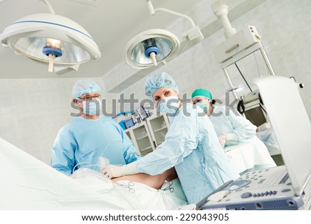 Team of surgeon in uniform perform varicose veins correction operation on a patient at surgery clinic