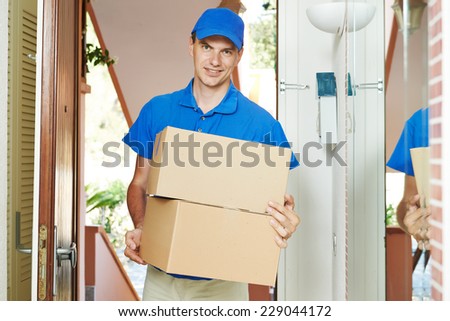 Smiling male postal delivery courier man indoors delivering parcel package boxes