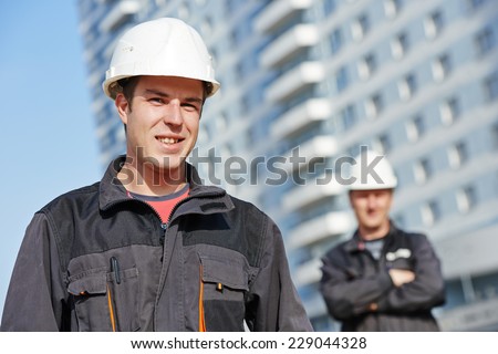 Team of smiling foreman builders workers in protective uniform at construction building site
