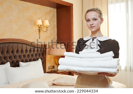 Hotel service. female housekeeping worker with towels and bedclothes at inn room