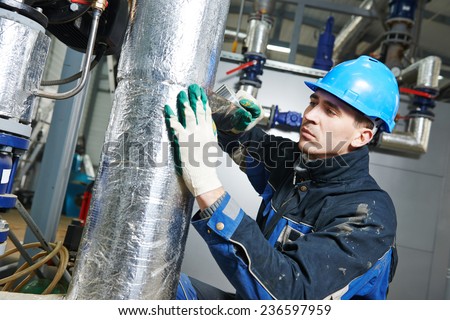 industrial construction worker at boiler room pipe heat insulation work