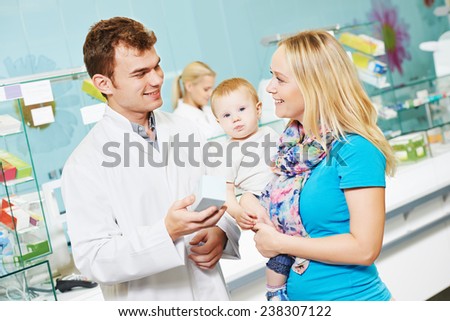 Cheerful pharmacist chemist man giving vitamins to woman with child in pharmacy drugstore