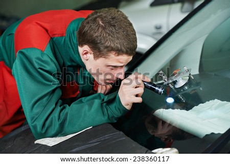 Automobile glazier repairman repairing windscreen or windshield of a car in auto service station garage