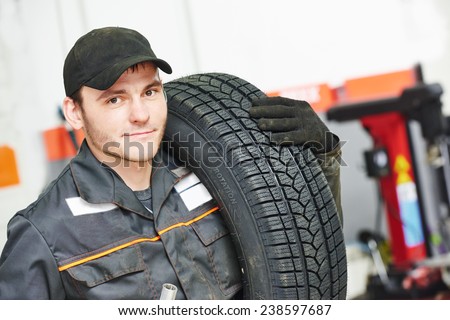 repairman mechanic portrait in car auto repair or maintenance shop service station with automobile wheel tire