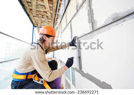 builder worker works with facade joint of building with plaster and spatula