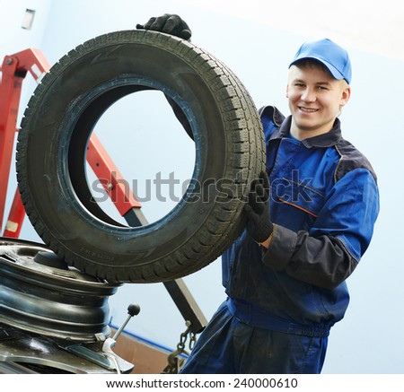 Auto repairman portrait with automobile car wheel tyre at during tire replacing on fitting machine