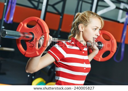 Young woman training exercises with weight bar in fitness club gym
