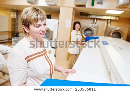 Hotel linen cleaning services. Woman with ironing machine working
