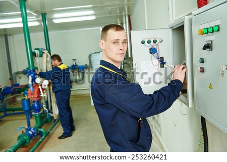 electrician in front of fuseboard equipment together with heating engineer in bioler room