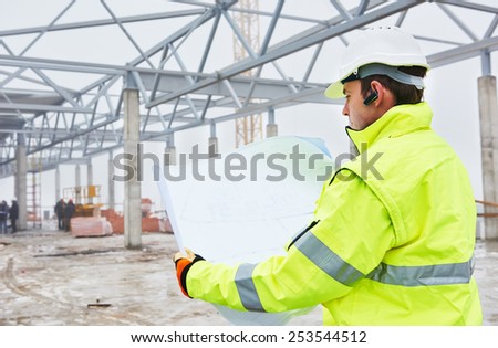 male engineer construction foreman manager outdoors indoors at building site with blueprints