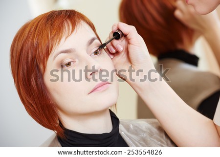 Makeup technique. mascara eyelashes of redheaded woman in beauty salon