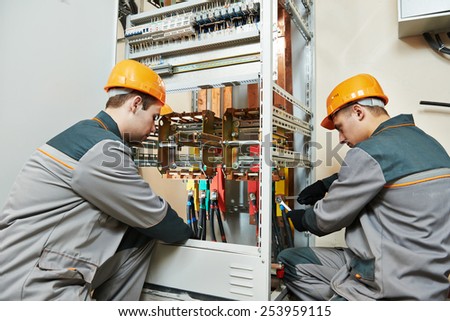 two electrician builder engineer works with electric cable wiring of fuse switch box