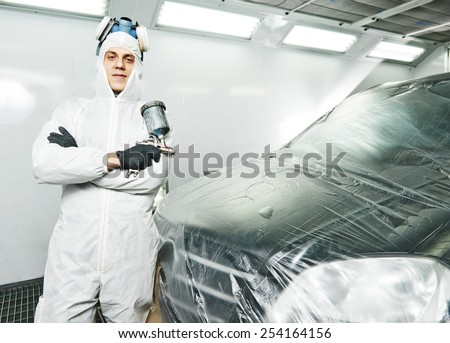 automobile repairman painter painting car body bumper in chamber