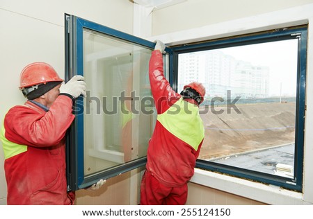 Two male industrial builders workers at window installation