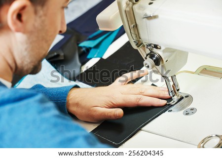 male tailor working with sewing machine and cloth in workshop