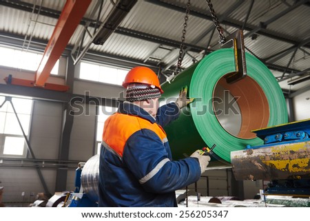 industrial worker operating metal sheet profiling mechine at manufacturing factory