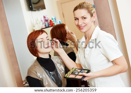 Makeup technique. specialist works with mascara eyelashes of redheaded woman in beauty salon