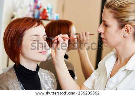 Makeup technique. specialist works with mascara eyelashes of redheaded woman in beauty salon