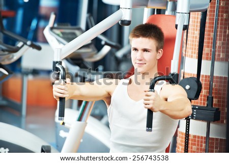 fitness man at chest pectoral muscles exercises with training weight machine station in gym