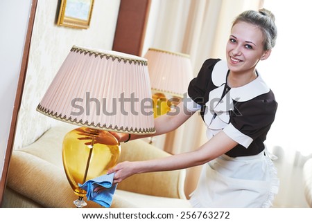 Hotel service. female housekeeping worker with cleaning table from dust in room