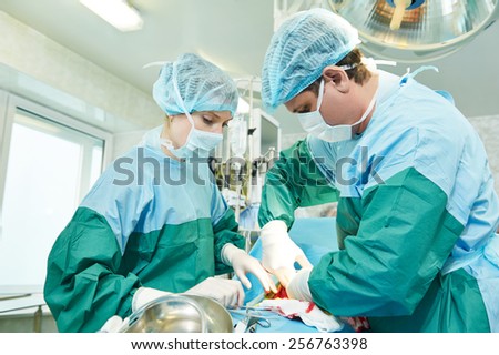 surgeons perfoming surgery operation of abdominal cesarean section during child delivery birth at clinic operating room