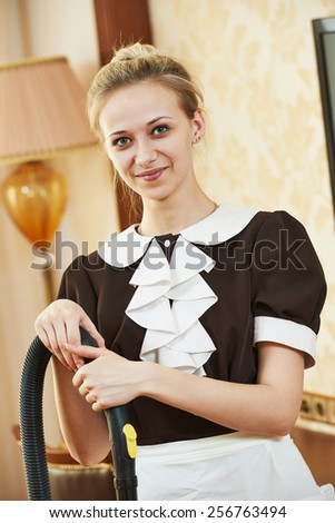 Hotel service. Portrait of female housekeeping or housemaid with vacuum cleaner at inn room