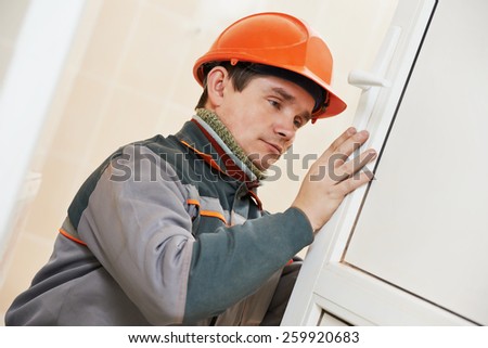 Male worker handyman carpenter at lock installation into wood door